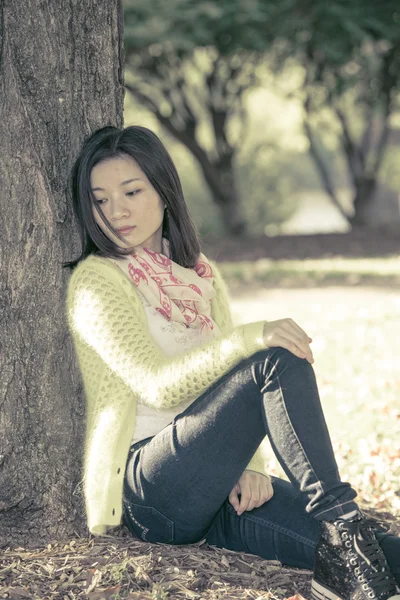 Woman sitting against a tree — Stock Photo, Image