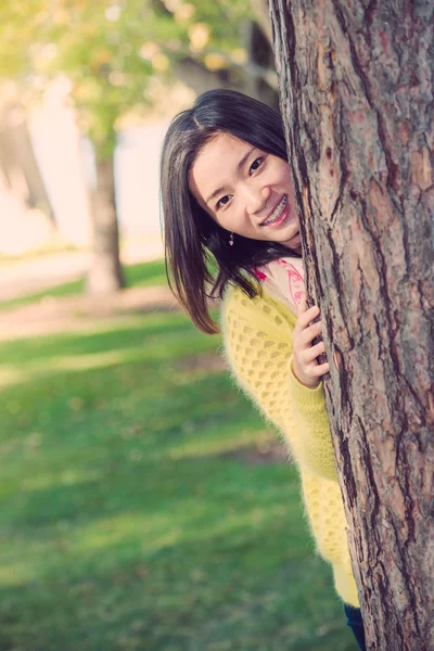 Mujer escondida detrás de un árbol — Foto de Stock