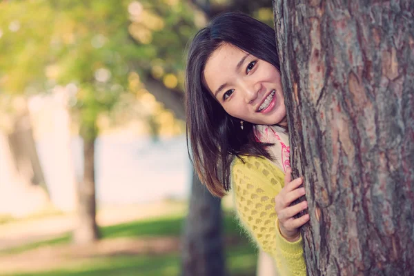 Vrouw verschuilt zich achter een boom — Stockfoto