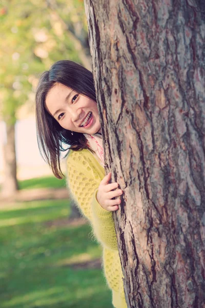 Woman hiding behind a tree — Stock Photo, Image