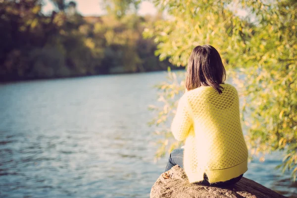 Femme assise à côté d'une rivière — Photo