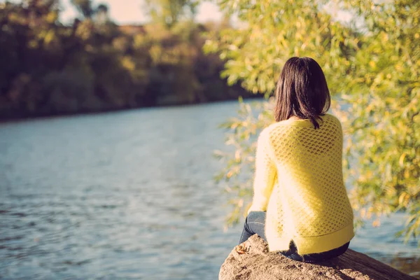 Femme assise à côté d'une rivière — Photo
