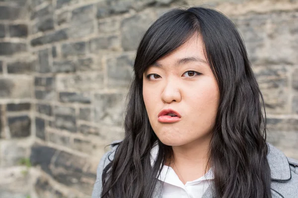 Angry woman by a stone wall — Stock Photo, Image