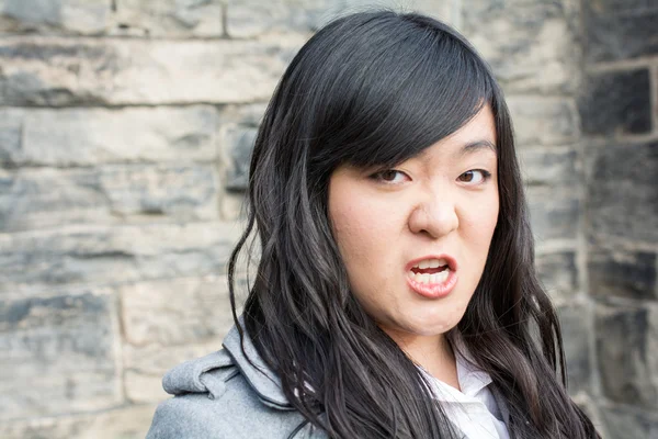 Angry woman by a stone wall — Stock Photo, Image