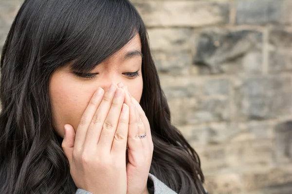 Mujer triste por una pared de piedra — Foto de Stock