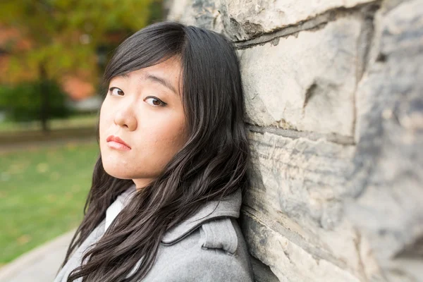 Sad woman by a stone wall — Stock Photo, Image