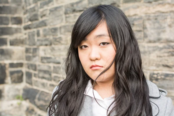 Sad woman by a stone wall — Stock Photo, Image