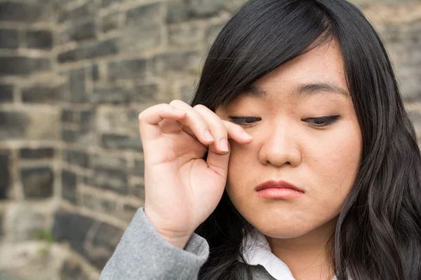 Mujer triste por una pared de piedra — Foto de Stock