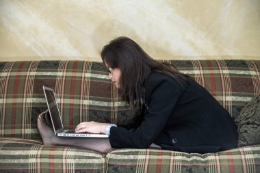 kadın kanepede dizüstü bilgisayarda yazarak