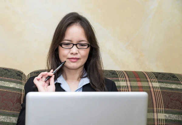 Vrouw met pen en laptop op sofa — Stockfoto