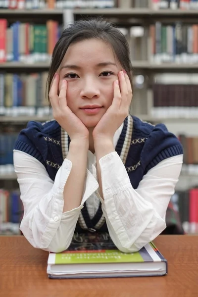 Student sitzt am Schreibtisch in der Nähe der Bibliothek — Stockfoto
