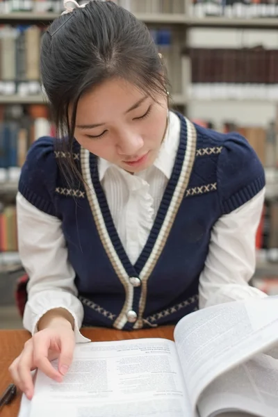 Student lezing leerboek in de buurt van boekenplank — Stockfoto