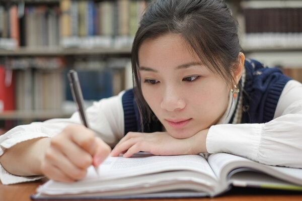 Tired student doing homework in library