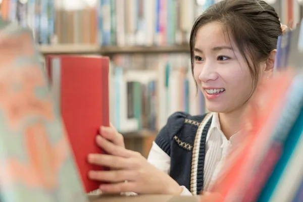 Chica escogiendo un libro rojo —  Fotos de Stock