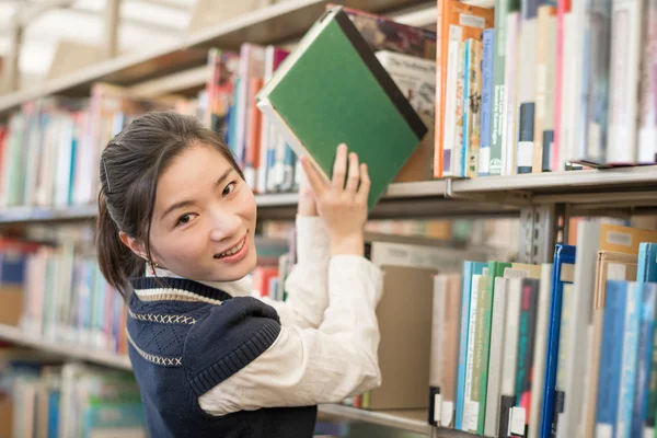 Woman taking a book from a bookshelf — Stock Photo, Image