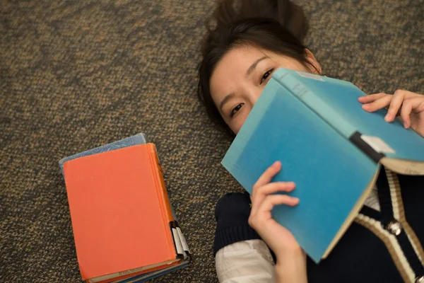 Studente posa su tappeto con libri — Foto Stock