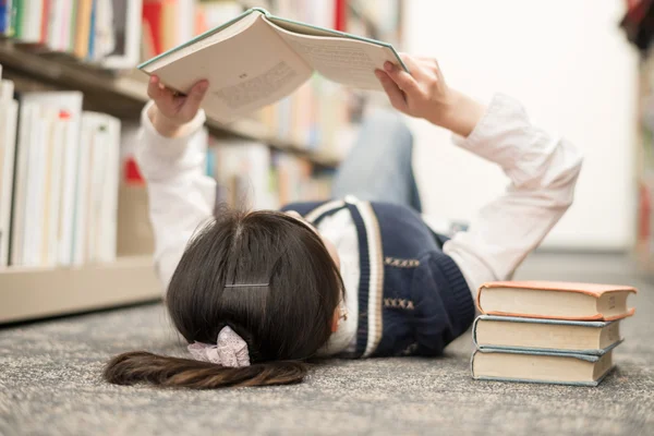 Student laying on floor reading book — Stock Photo, Image