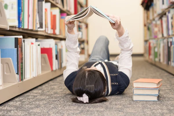 Student laying on floor reading book — Stock Photo, Image