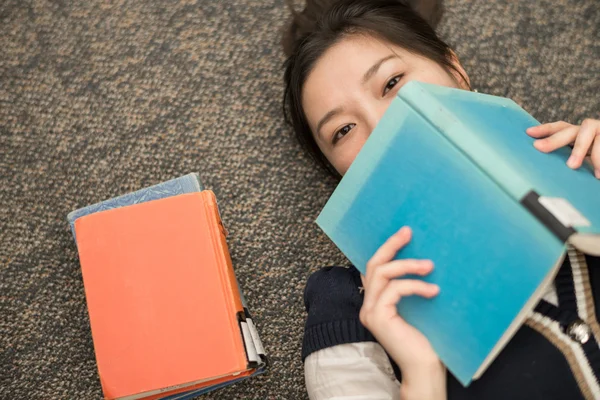 Studente posa su tappeto con libri — Foto Stock