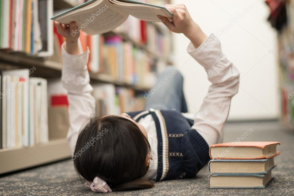 Student laying on floor reading book
