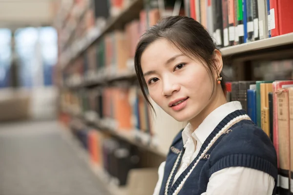 Femme assise sur le sol à côté de la bibliothèque — Photo