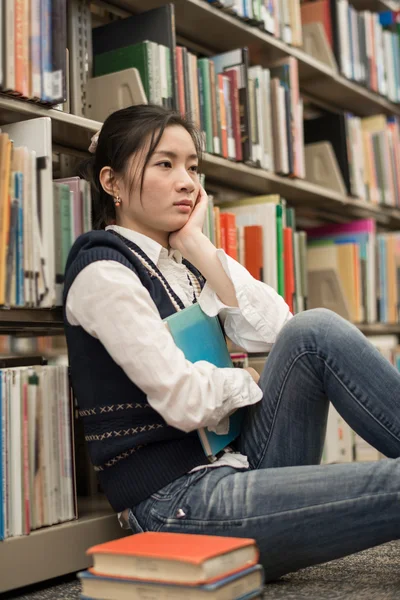 Student naast boekenplank op zoek depressief — Stockfoto