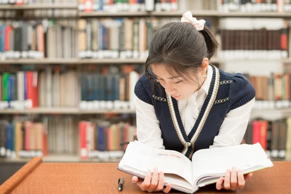 Estudiante leyendo un libro de texto en la biblioteca —  Fotos de Stock