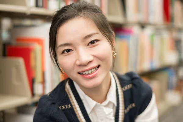 Портрет девушки, улыбающейся в библиотеке — стоковое фото