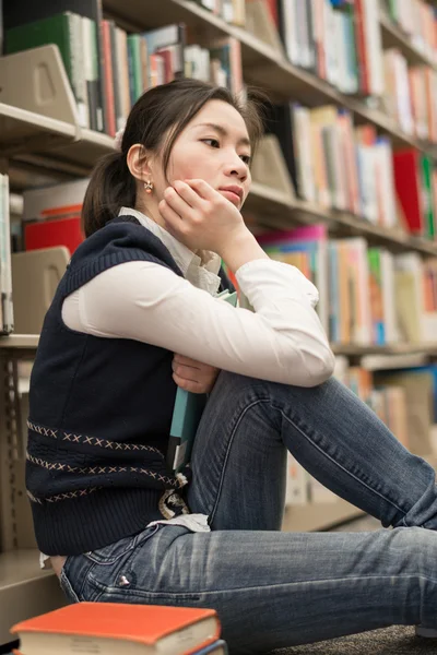 Student naast boekenplank op zoek depressief — Stockfoto