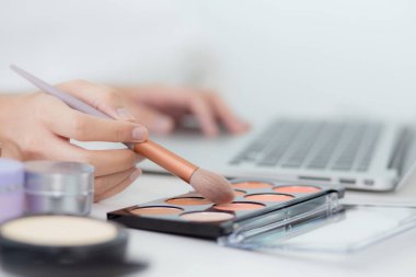 Makyaj yapmayı öğrenen kadınların elleri, yanaklarına sürtünerek dizüstü bilgisayarda özel ders veren, bayan öğretmenlik yapan, makyaj paletiyle makyaj yapan ve sosyal medyada makyaj yapan kadınların elleri..