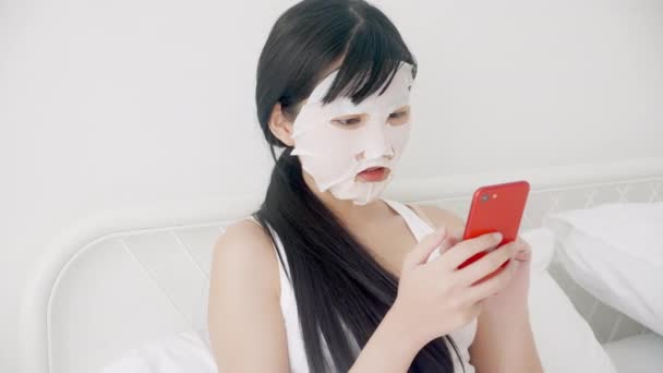 Hermosa Mujer Asiática Joven Con Mascarilla Facial Sábana Sentado Viendo — Vídeos de Stock