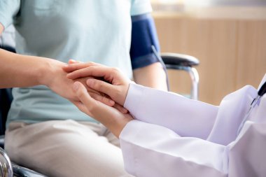 Doktor kadınların kapalı elleri, yaşlı hastaları hastanede tekerlekli sandalyeye oturtmayı, doktorların yaşlıları, teşhis hastalıklarını ve hastalıkları teselli etmek için el ele tutuşmayı ve bakmalarını teşvik eder..