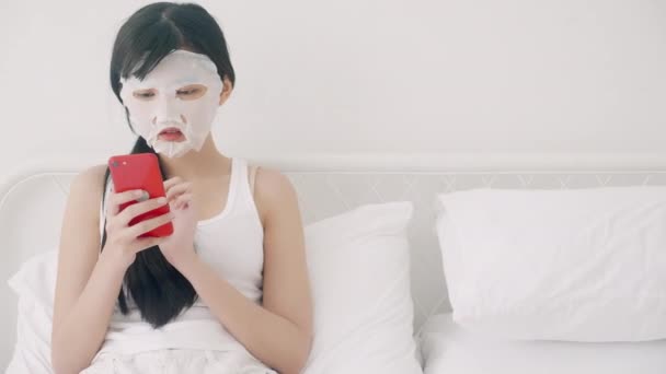 Hermosa Mujer Asiática Joven Con Mascarilla Facial Sábana Sentado Viendo — Vídeo de stock