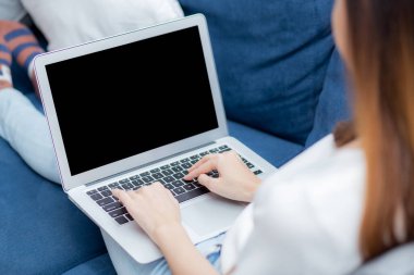 Genç Asyalı kadın evde dizüstü bilgisayarlı boş ekran maketi ile çalışıyor, boş not defteri kullanan serbest çalışan kız klavye yazıyor ve multimedya, iş ve iletişim konseptiyle rahatlıyor..