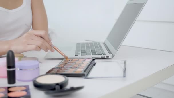 在笔记本电脑上用笔刷着学习化妆的女人的手 在线辅导课程 女性的教学和解释 在流线型社交媒体上用化妆品和化妆品化妆 — 图库视频影像