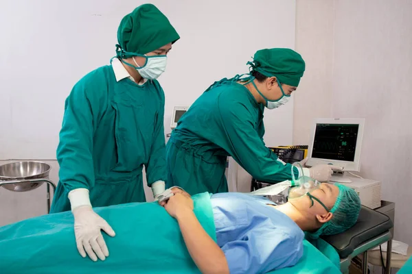 病院の手術室での患者の緊急時におけるチーム医師とアシスタントの準備手術と酸素マスク 監視付き外科医の治癒と手術 呼吸の問題 — ストック写真