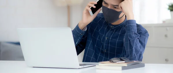 Młody Azjatycki Biznesmen Masce Twarzy Mówi Smartfon Pracuje Laptopie Ochrony — Zdjęcie stockowe