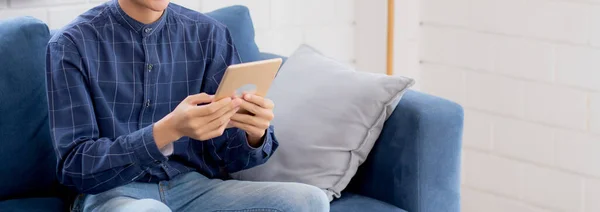 若い魅力的なアジアの男は自宅でソファにタブレットコンピュータを使用して休んで 幸せな男性はソファに座ってリラックスして読書デジタルガジェットで家 コミュニケーションとライフスタイルの概念 — ストック写真