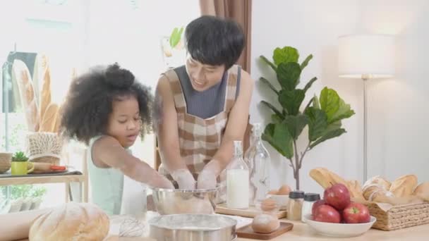 家庭で一緒に台所で娘と一緒に料理やダンスのためのエプロンのスリッシュな小麦粉を身に着けている母親とアフリカ系アメリカ人の家族 楽しさと遊び心のある食べ物を準備親と小さな子供 — ストック動画