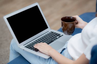 Genç Asyalı kadın evde dizüstü bilgisayarlı boş ekran maketi ile çalışıyor, serbest çalışan kız boş defter kullanıyor ve kahve içiyor, kız multimedya, iş ve iletişim konseptiyle rahatlıyor.