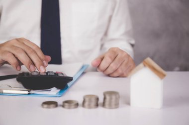 İşadamı, yatırımla ilgili hesap makinesi ile hesaplar ve panoda ve ev modelinin masa, sigorta ve finans üzerinde olması, gayrimenkul ve konut ve iş konsepti hakkında planlama,.