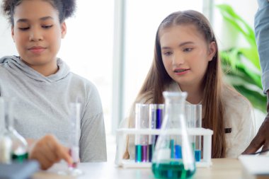 Genç öğretmen grup öğrencilerine okulda sıvı için bilim ve test kimyasalları öğretiyor, çocuklar laboratuarda deney bilimi okuyor ve öğreniyor, eğitim konsepti.