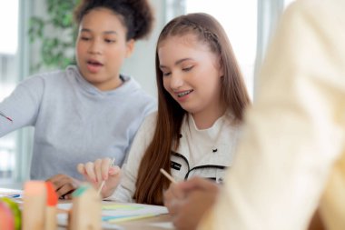 Bir grup öğrenci okulda öğretmenle birlikte oturuyor, çalışıyor ve resim çiziyor, öğrencilerin yaratıcılığı ve gelişimi kursta, okula, eğitim konseptine geri dönüyor..