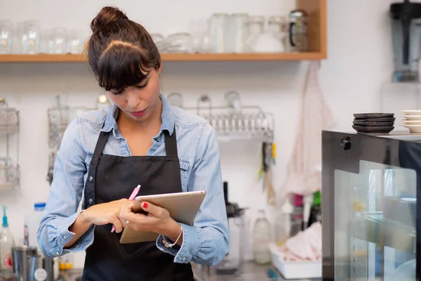 Genç kadın, kafeye çevrimiçi sipariş iletimi için tablet bilgisayar kullanıyor, girişimci ve küçük işletme, çalışan veya mal sahibi, teknoloji kavramından ticari ve girişim işi.