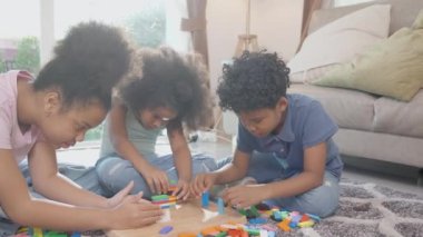 Çocukların olduğu mutluluk ailesi, eğlence ve eğlence ile birlikte yerde blok tahtası oynuyorlar ve evdeki oturma odasında rahatlıyorlar. Rekabet ve gelişim ve öğrenim için aktivite ve hobi, yaşam tarzı konsepti..