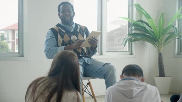 持有数码平板电脑的非洲教师在学校教授和解释小组学生 返回学校 学生坐在地板学习和课堂学习 教育理念 — 图库视频影像