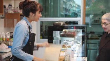 Müşteri kıdemli kadın kahvesini ve yemeğini kahvesini kafede sipariş ediyor. Müşteriler için kahve ve yemek servisi yapıyor. Personel yaşlılarla, küçük işletmelerle içki dağıtıyor..
