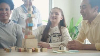 Genç öğretmen ve öğrenci kalkınma için blok tahtası oynuyorlar. Okulun sınıfında eğleniyorlar ve eğleniyorlar. Okula geri dönüyorlar, eğitim kavramına dönüyorlar..