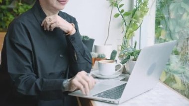 Kahvecide dizüstü bilgisayarda çalışan Asyalı son sınıf öğrencisi bir kadın, yaşlı bir iş kadını ya da interneti internetten rahatlamak için kullanan serbest çalışan bir iş kadını, işe başlama ve iletişim konsepti.
