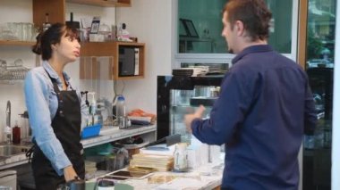 Müşteri kızgın ve barista kadın şikayet ederken kafede sipariş ve hizmet vermekten, mal sahibinin durumu ve stresinden, müşterinin hoşnutsuzluğundan ve kahve dükkanındaki garsonla görüşmesinden bıkmış..